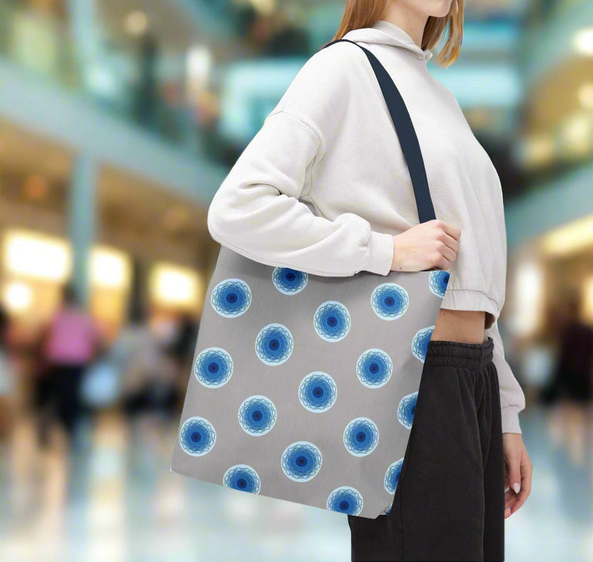 Woman holding a tote bag with a fish eye whirpool polka dot graphic pattern in a blurred shopping mall setting