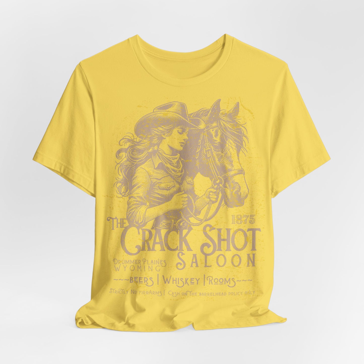 Yellow t-shirt with a graphic of a woman in a cowboy hat and horse, and text 'The Crack Shot Saloon' on a white background.