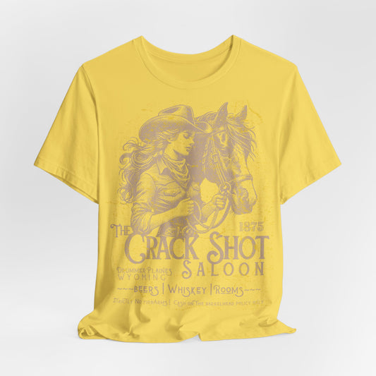 Yellow t-shirt with a graphic of a woman in a cowboy hat and horse, and text 'The Crack Shot Saloon' on a white background.