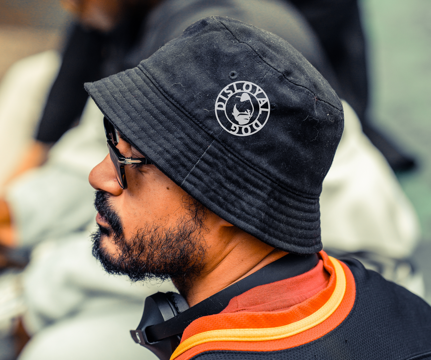 Person wearing a Disloyal Dog black bucket hat with the white/grey Duisloyal Dog logo.