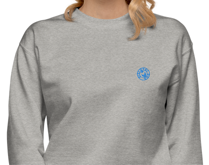 Woman wearing a light gray sweatshirt with a light blue Disloyal Dog logo on the left side of the chest.